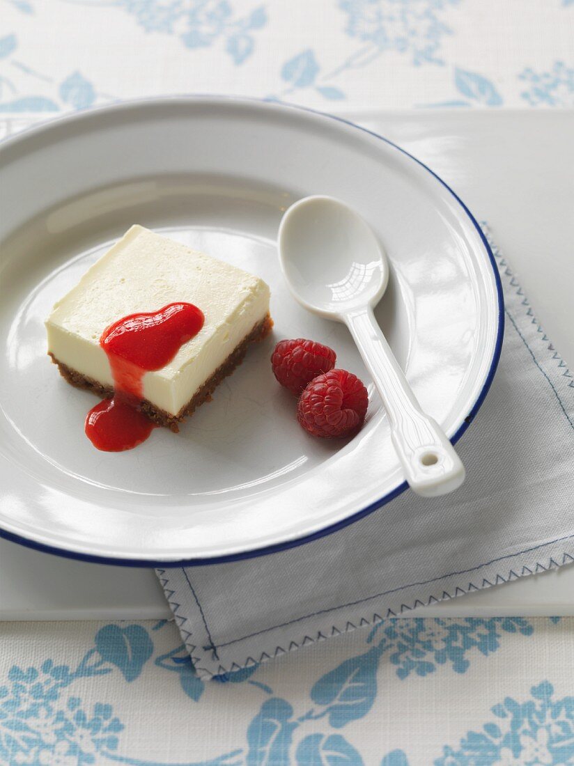 A panna cotta slice with raspberries and fruit sauce