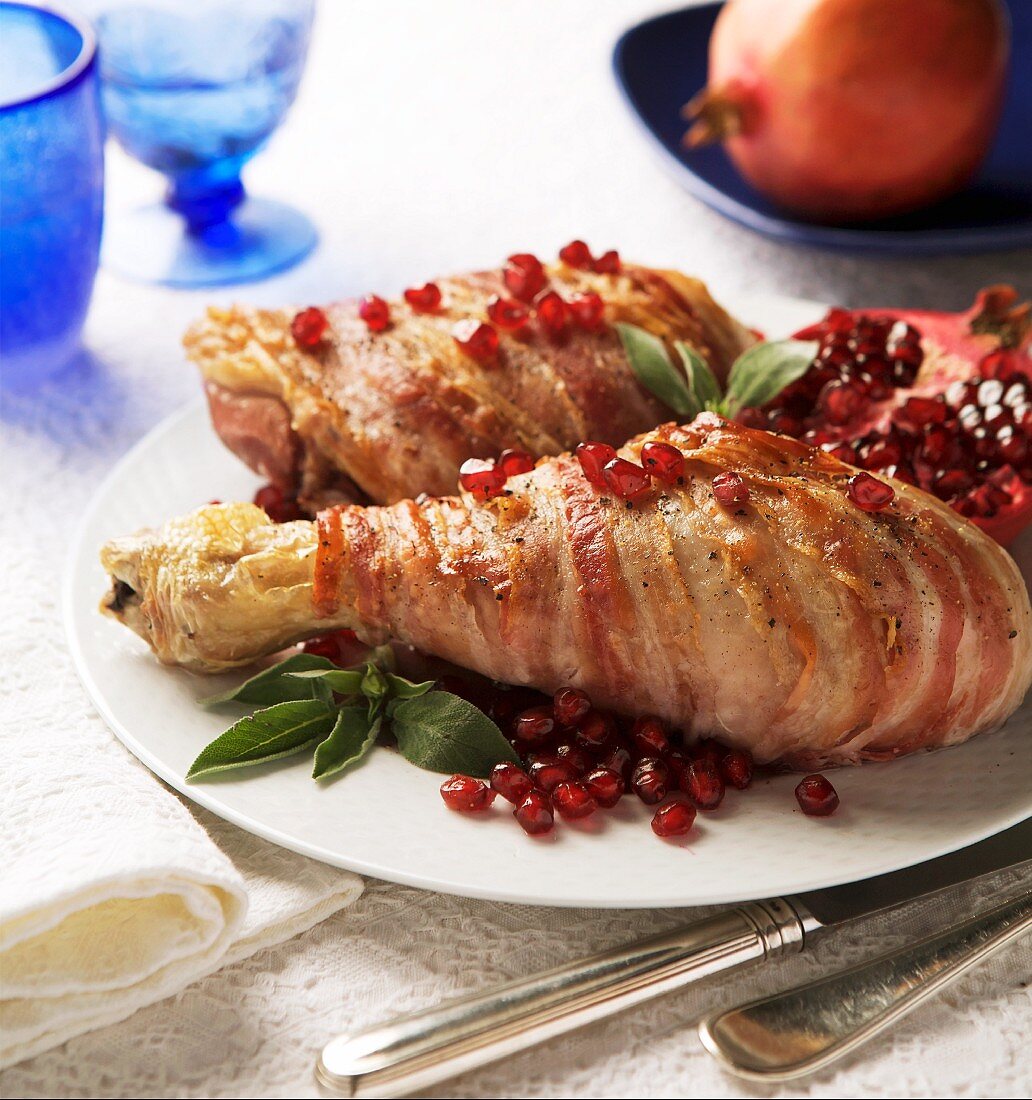 Turkey legs wrapped in bacon with pomegranate seeds and sage