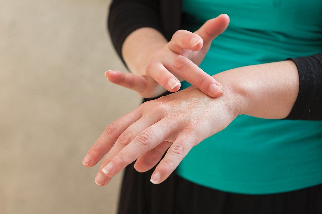 A woman applying a homemade balm made from bees wax, olive oil and essential lemon oil to her hands