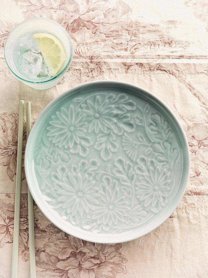 A floral patterned plate, chopsticks and lemon water (China)