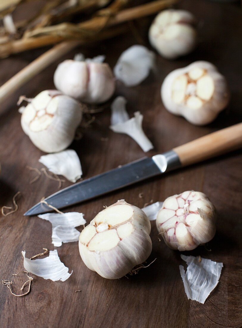 Bulbs of garlic, sliced, with a knife on a wooden surface