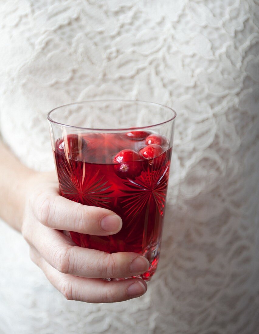 Frau hält ein Glas Cranberrysaft