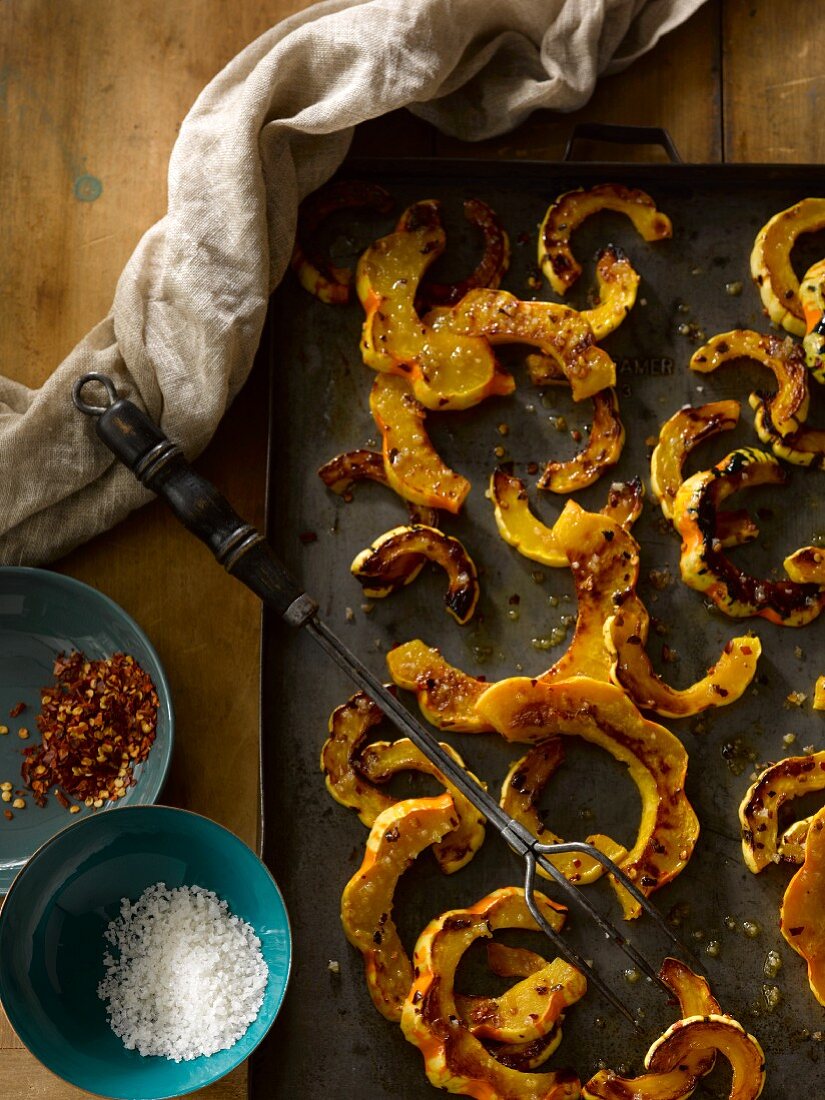 Roasted carnival squash on a baking tray with olive oil and spices
