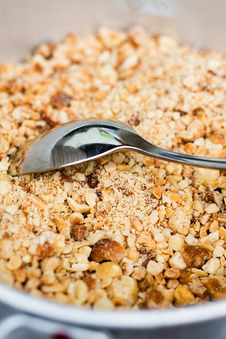 A bowl of nut brittle with a spoon