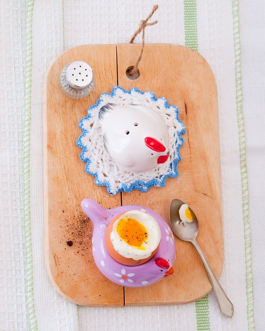 A boiled egg in an egg cup on a chopping board