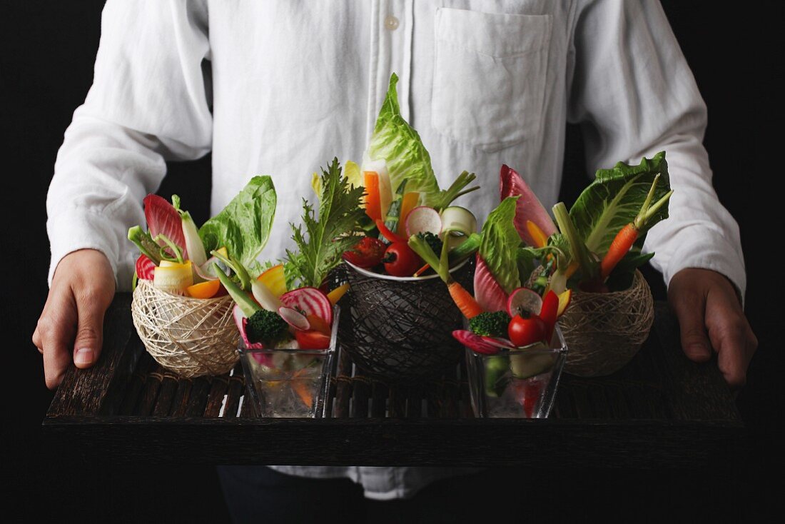 A man serving a tray of raw vegetables