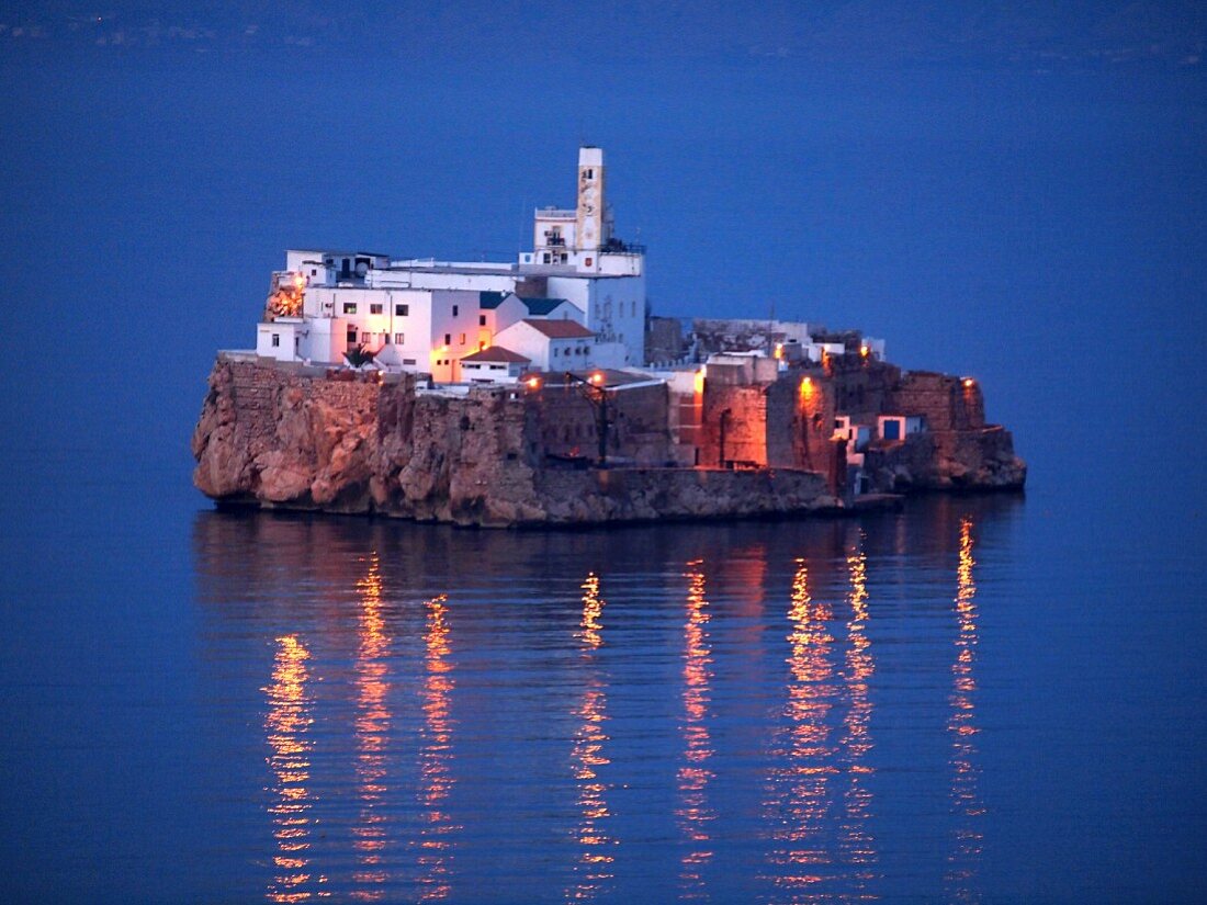 An evening view of the illuminated island of Penon de Alhucemas (Al Hoceima) 300 m from the Moroccan Mediterranean coast (belongs to Spain)