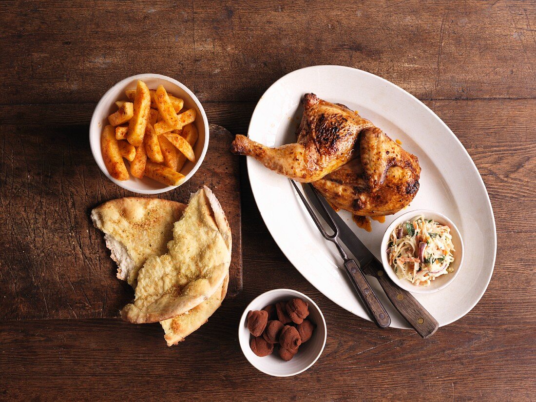 Grilled piri-piri chicken with side dishes and unleavened bread