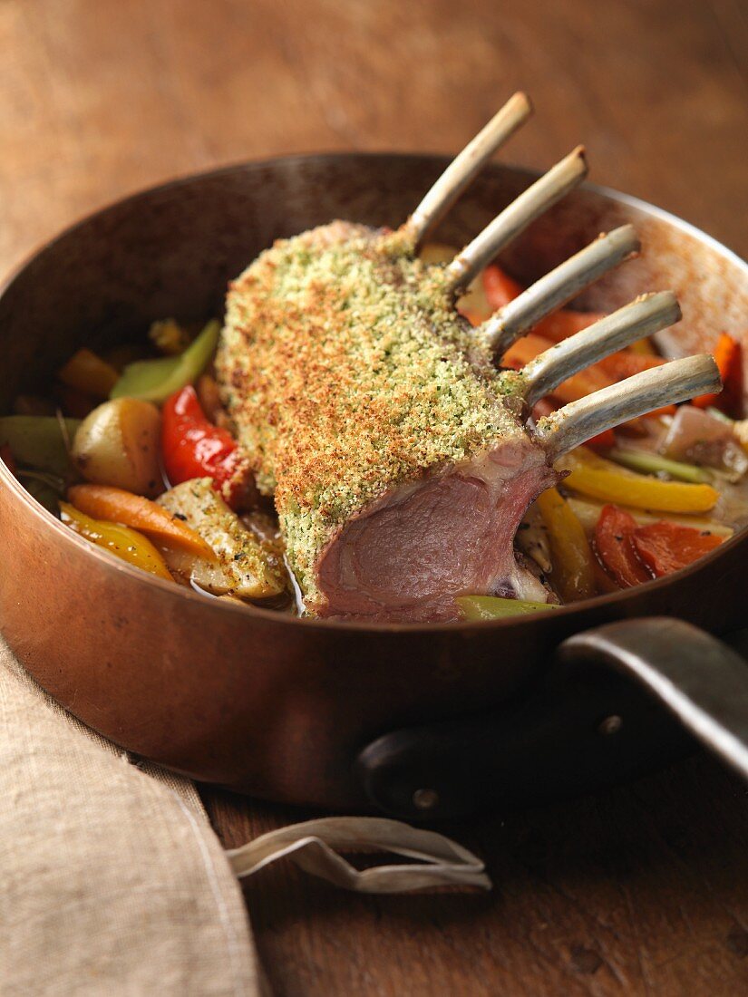 Saddle of lamb on a bed of vegetables in a copper pan