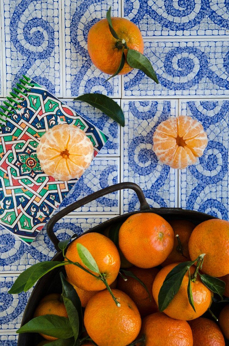 Tangerinen mit Blatt auf Fliesen mit ornamentalem Muster