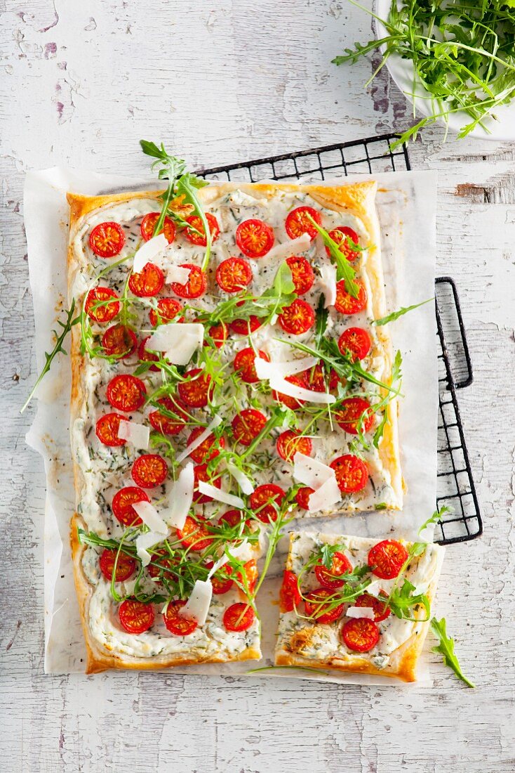 Puff pastry cake with herb cream, tomatoes, rocket and Parmesan