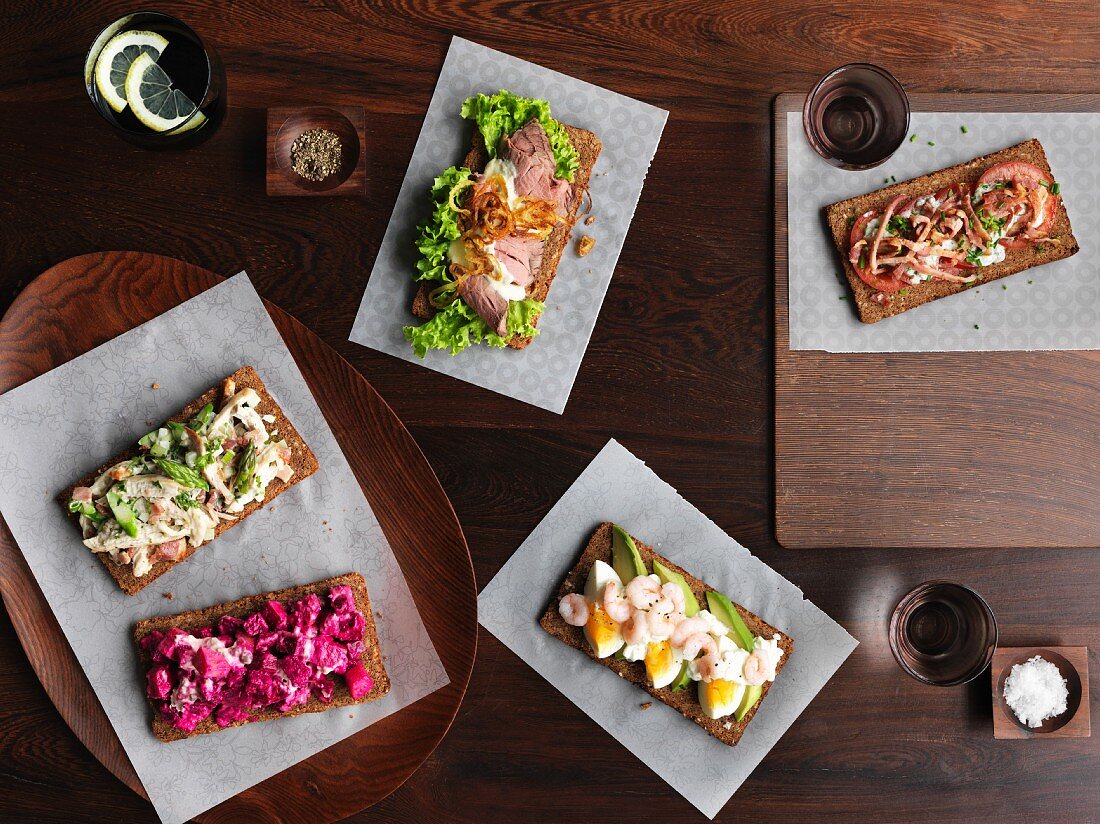 Smörrebröd with various toppings (Denmark) on a wooden table photographed from above