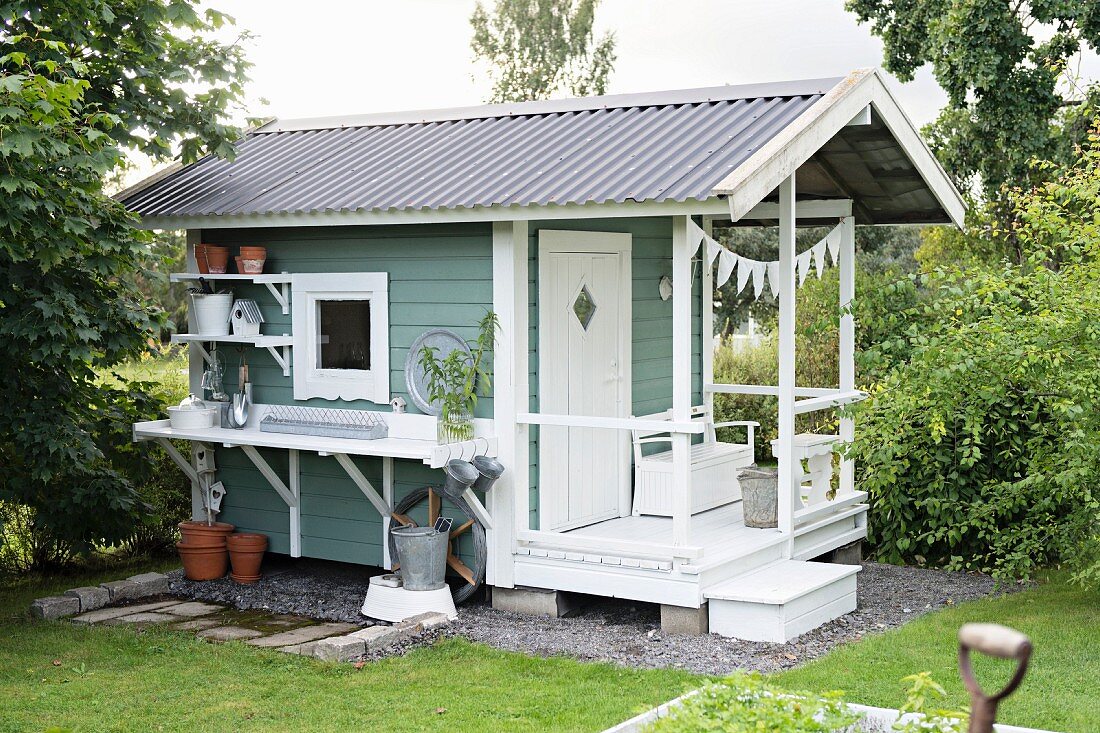 Swedish garden shed with porch and potting table and shelves on one side wall