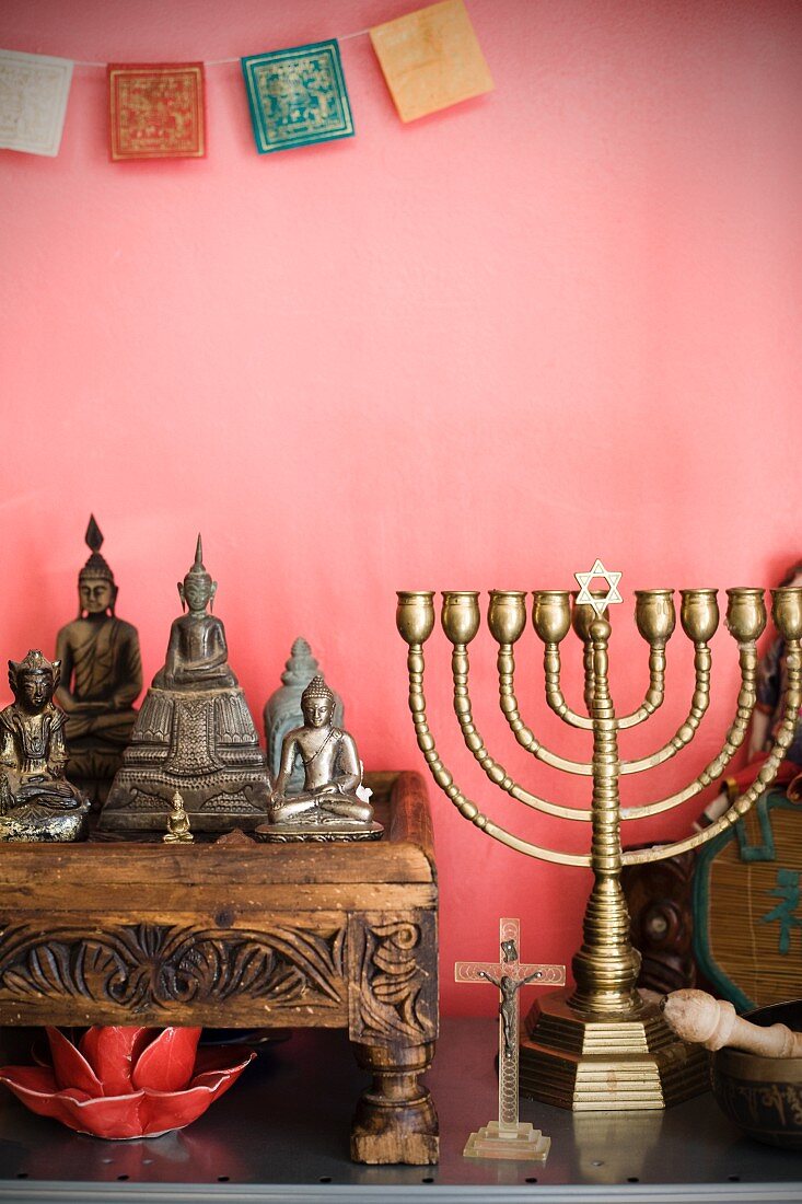 Sammlung unterschiedlicher, religiöser Symbole vor rosafarbener Wand