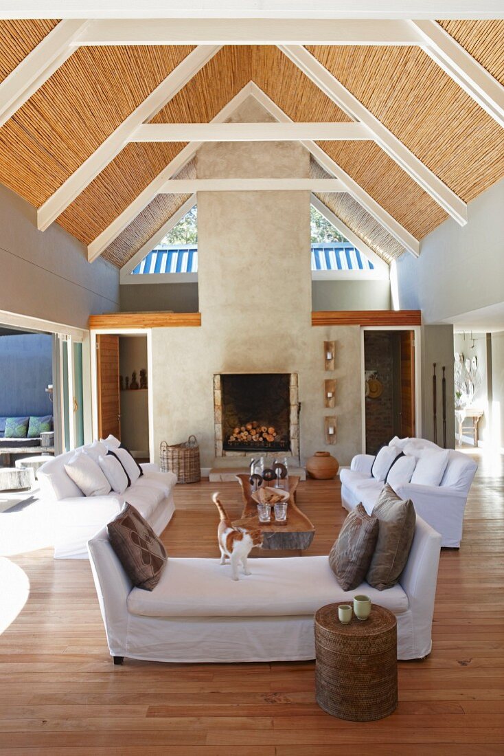 Open-plan interior with sofa set and exposed roof structure with bamboo roof covering in architect-designed house