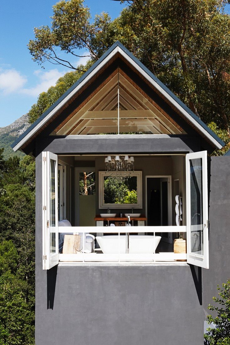 Modern house with grey façade, open folding sliding doors and view into bathroom