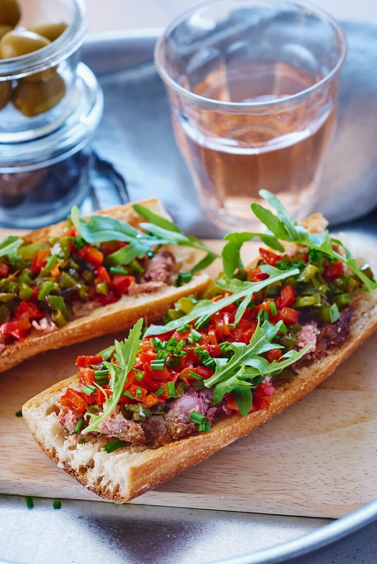 Baguettes topped with meat pâté, peppers and rocket