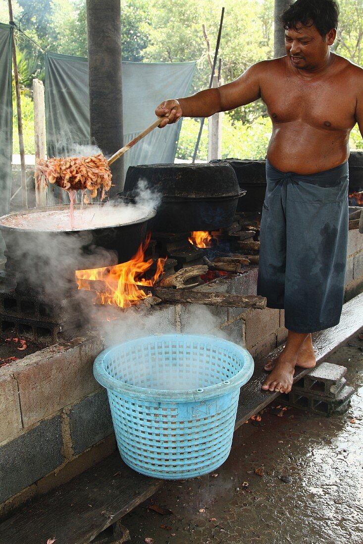 Mann beim Kochen von Garnelen, Thailand