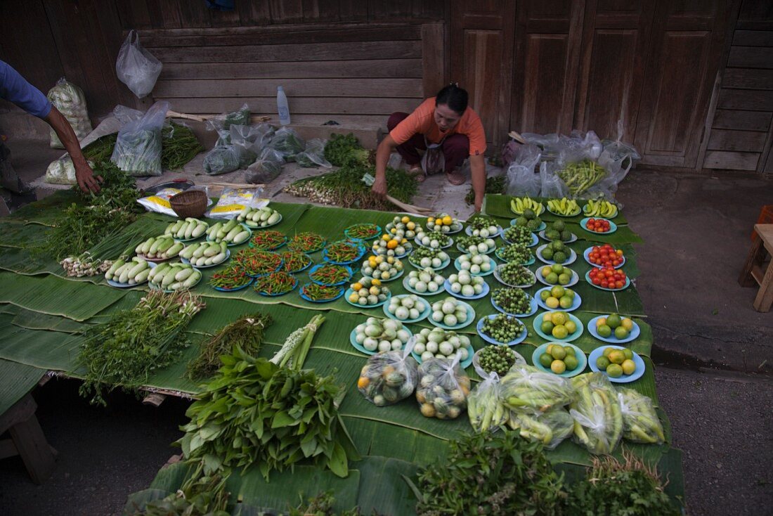 Marktstand mit frischem Obst und Gemüse auf frischen Bananenblättern, Thailand