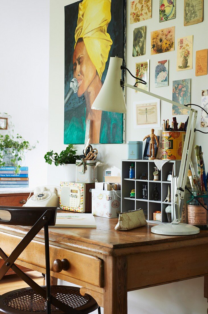 Old wooden desk below poster and postcards on wall