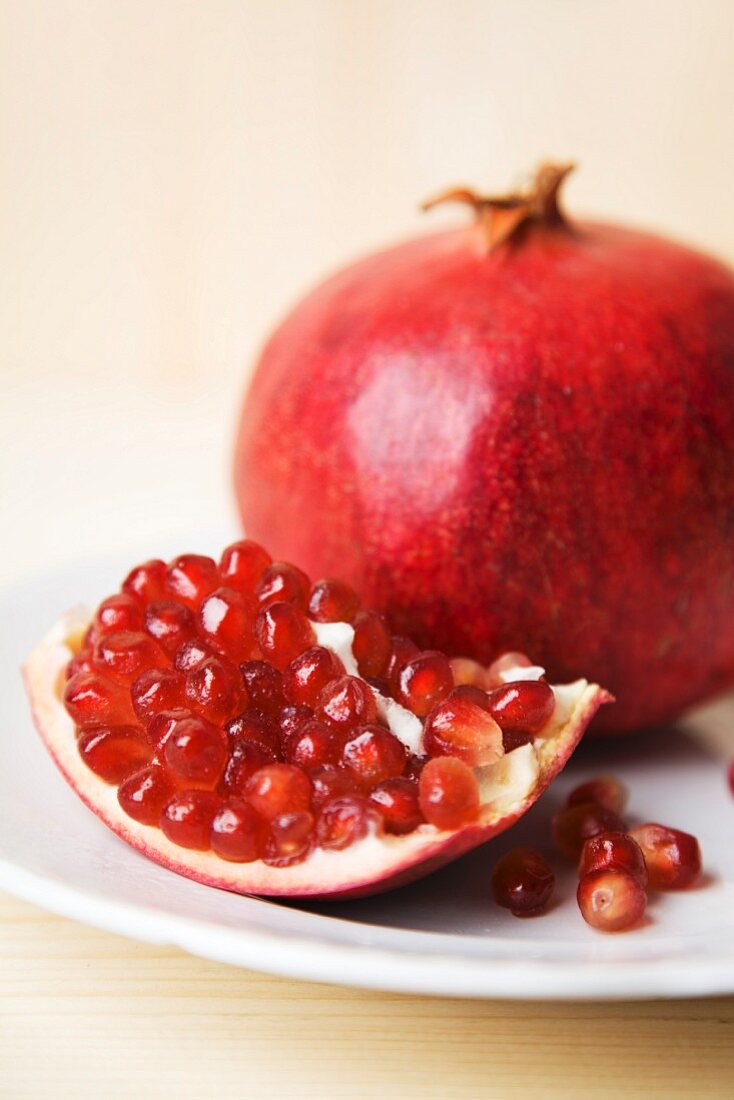 A piece of pomegranate and a whole pomegranate