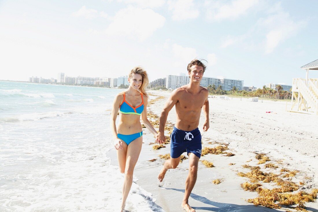 A young couple running along a beach