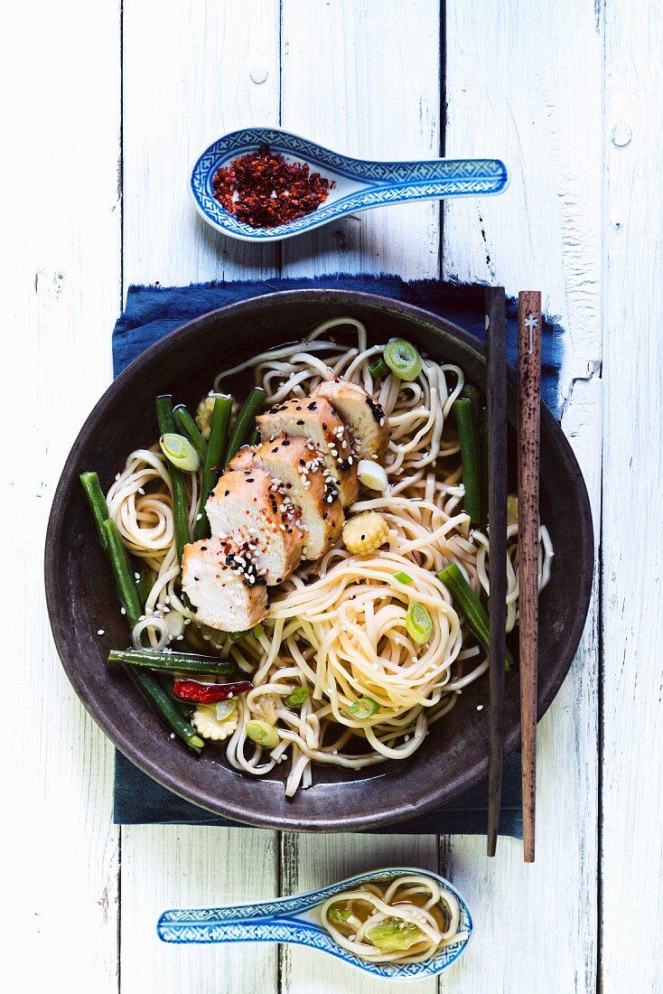 Chicken breast with spring onions and chilli peppers on a bed of noodles (Asia)