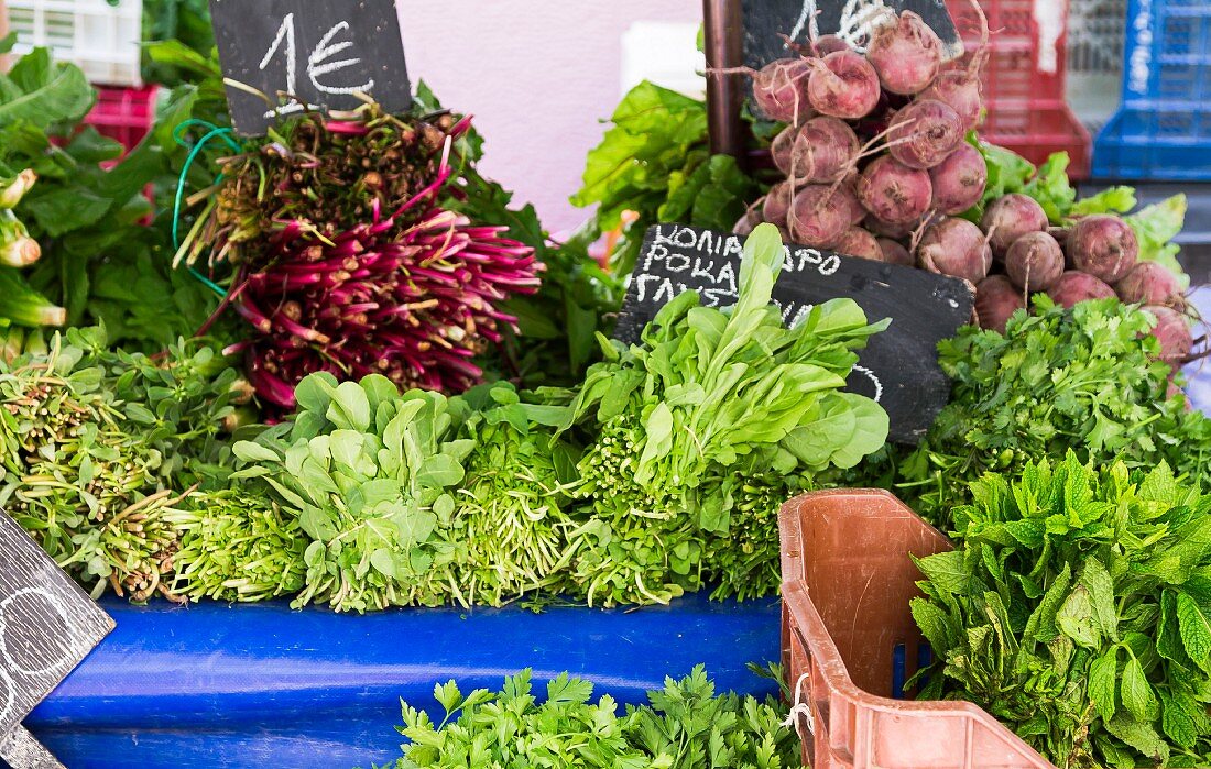 Leafy vegetables, root vegetables and fresh herbs on a vegetable stand