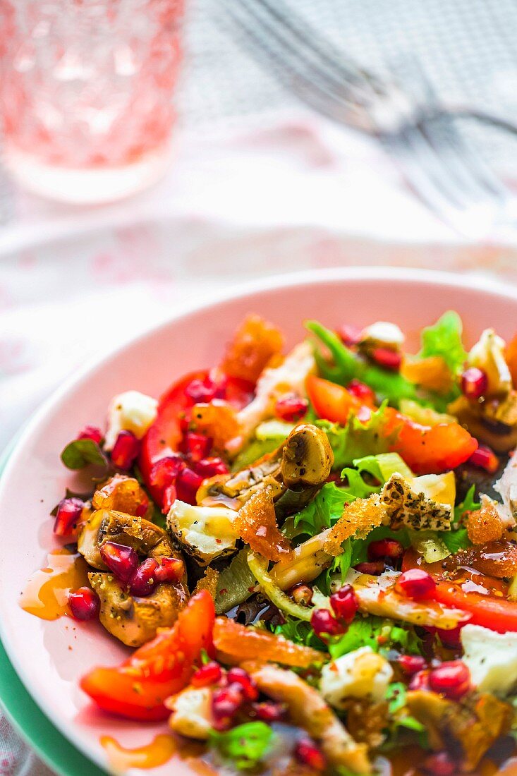 A colourful salad with quince bread, pomegranate, chicken, grilled mushrooms, herb cheese, tomatoes and apple vinegar