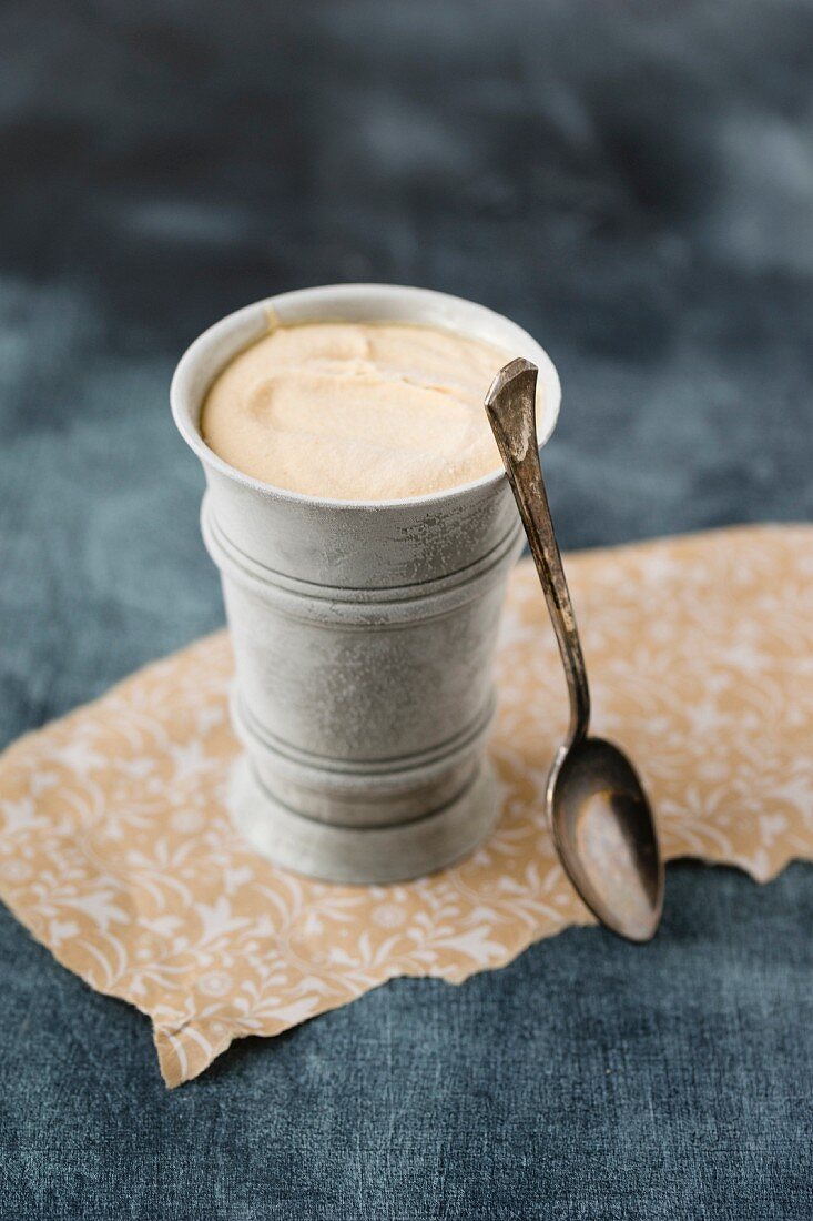 Caramel ice cream in a metal cup with a spoon