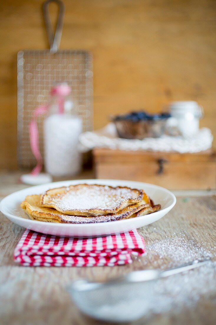 A stack of pancakes dusted with icing sugar