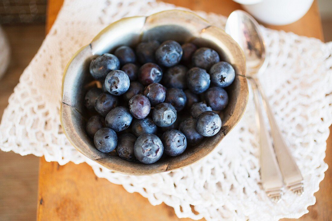 A bowl of fresh blueberries on a crocheted doily