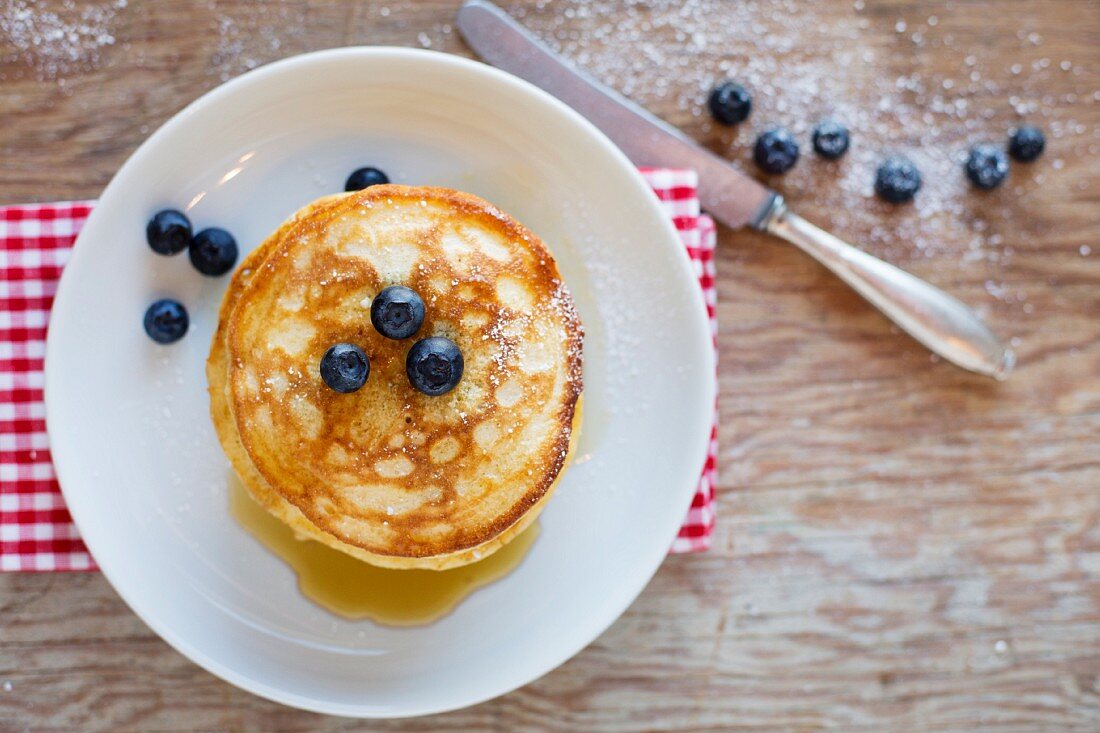 Gestapelte Pancakes mit Zucker und Heidelbeeren (Draufsicht)