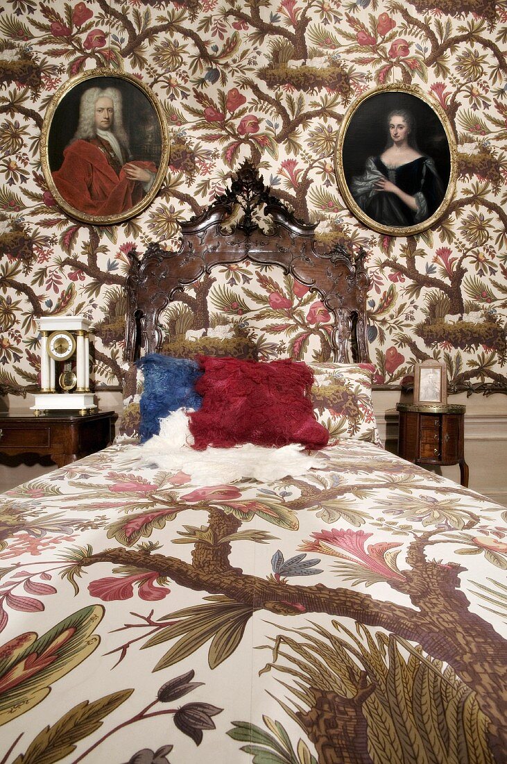 Herrschaftliches Schlafzimmer, Bettwäsche und Tapete mit gleichem floralem Muster, an Wand antike ovale Familienportraits
