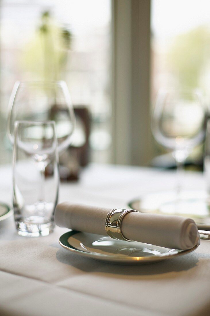 Teller mit Stoffserviette und leere Gläser auf Restauranttisch