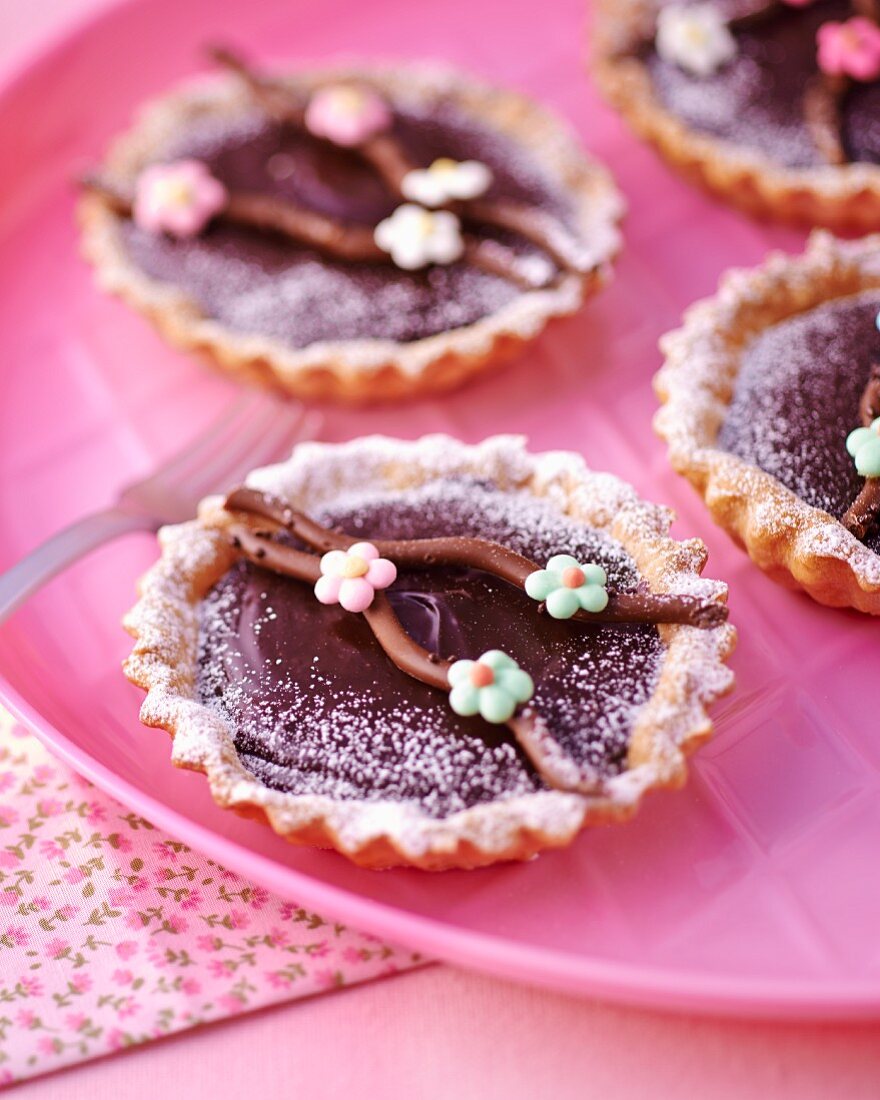 Schokoladentarteletts mit Zuckerblumen und Puderzucker