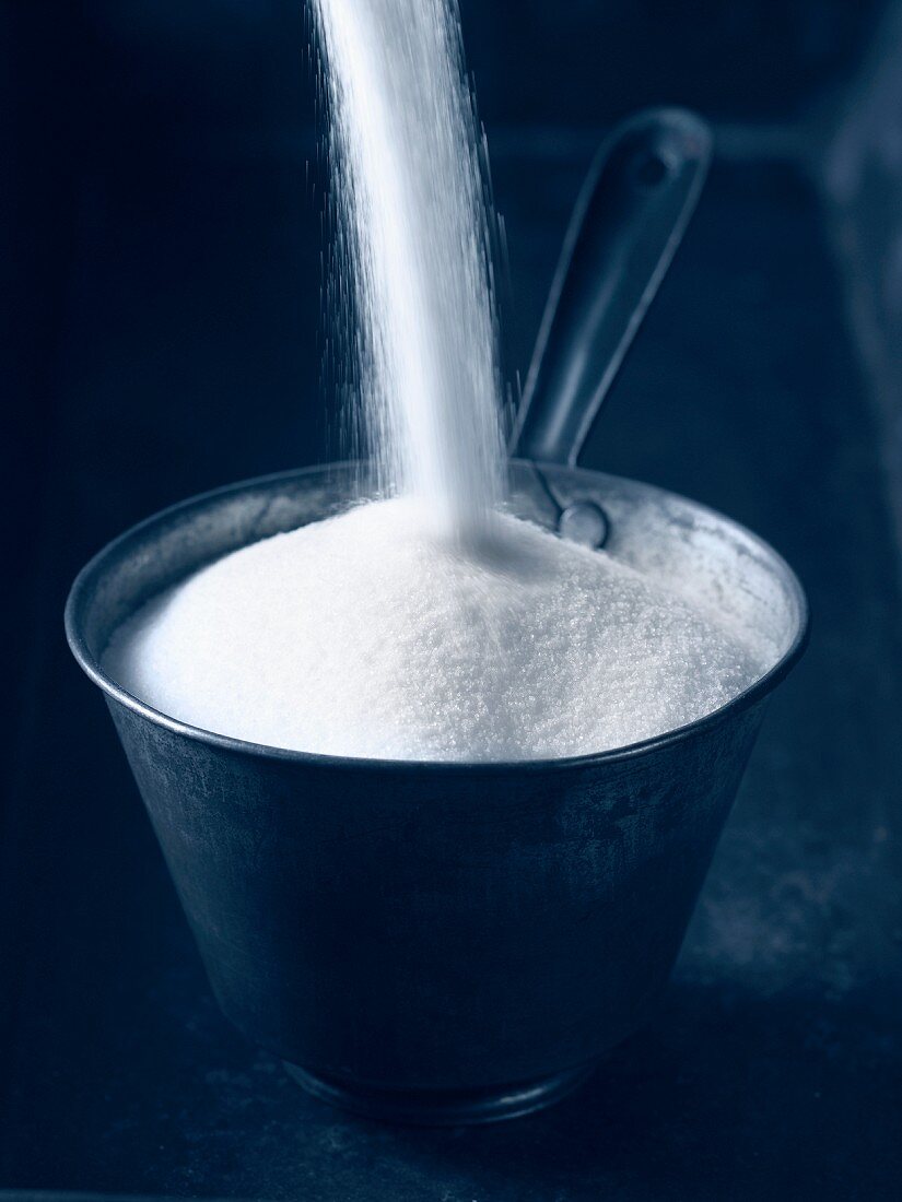 Zucker in Metallschale schütten