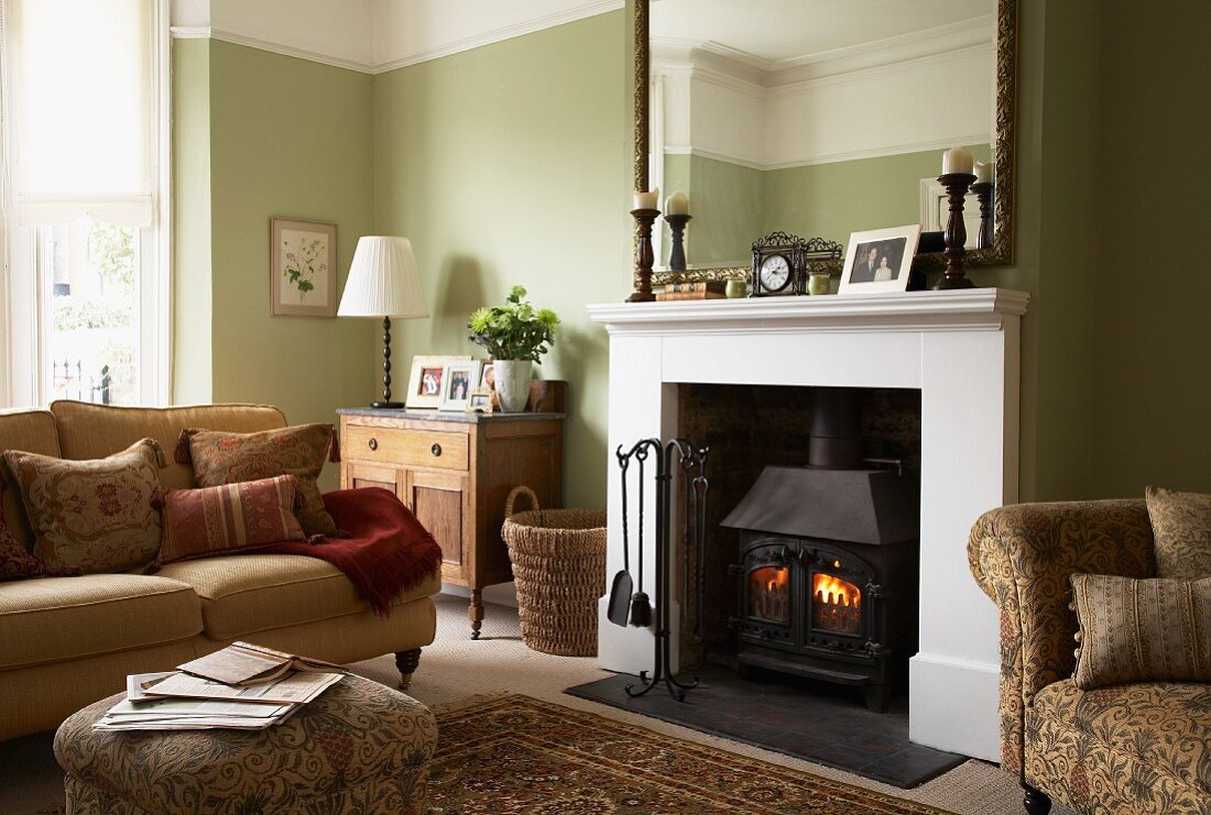 A cosy, traditional living room with a light green wall and a sofa in front of an open fireplace