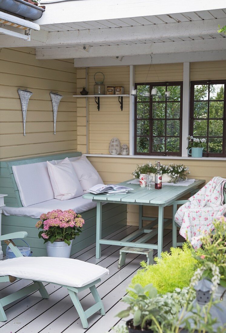 Bench and table in yellow loggia with white wooden floor