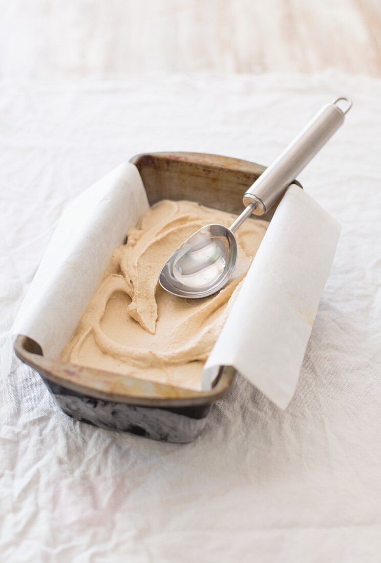 Vanille-Kaffee-Eis im Eisbehälter mit Eisportionierer