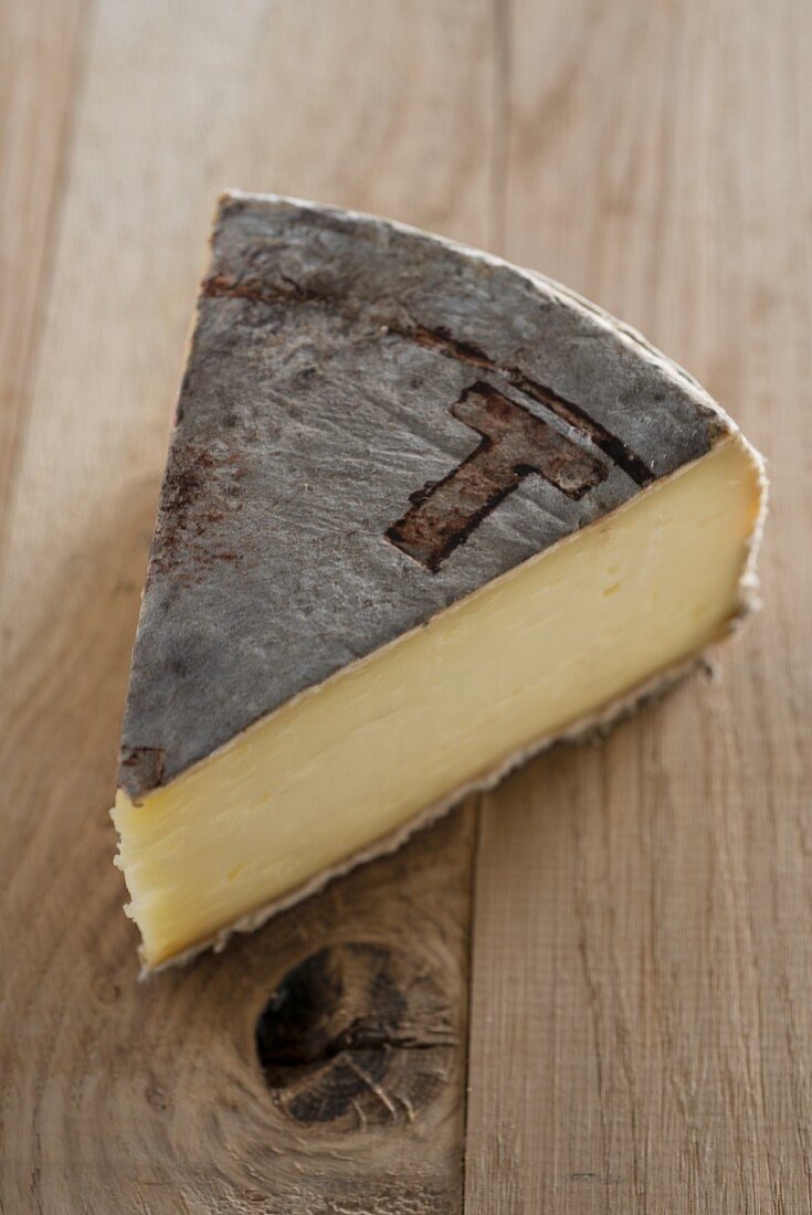 A slice of cow's milk cheese on a wooden surface