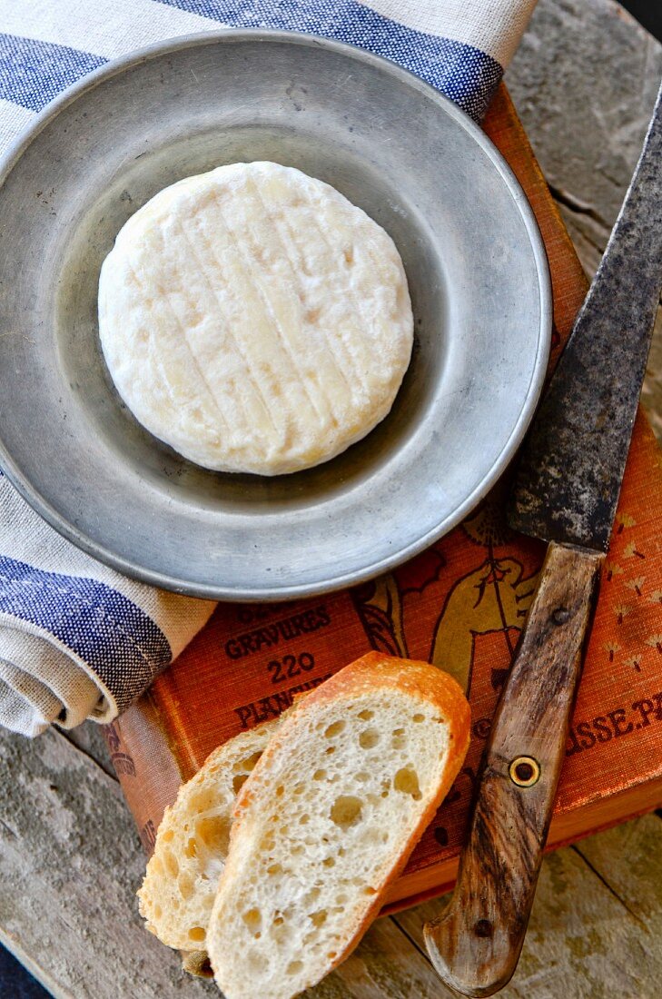 St. Marcellin cheese on a pewter plate with baguette