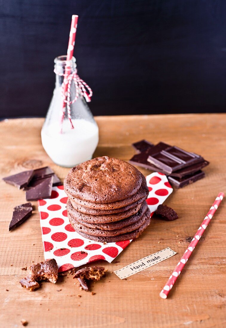 A stack of chocolate biscuits with a bottle of milk