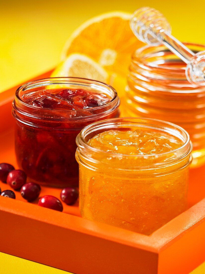 A jar of cranberry and orange marmalade and a jar of honey and lemon marmalade
