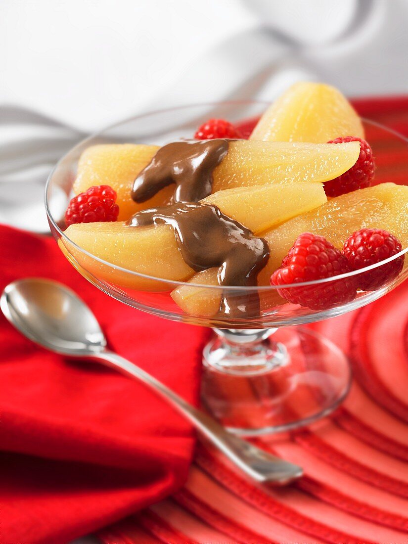 Poached pears with chocolate sauce and raspberries in a dessert bowl