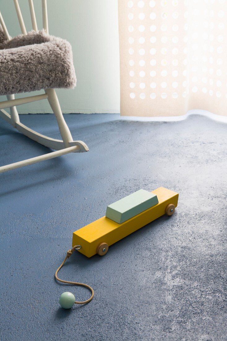 Painted wooden toy car on blue concrete floor