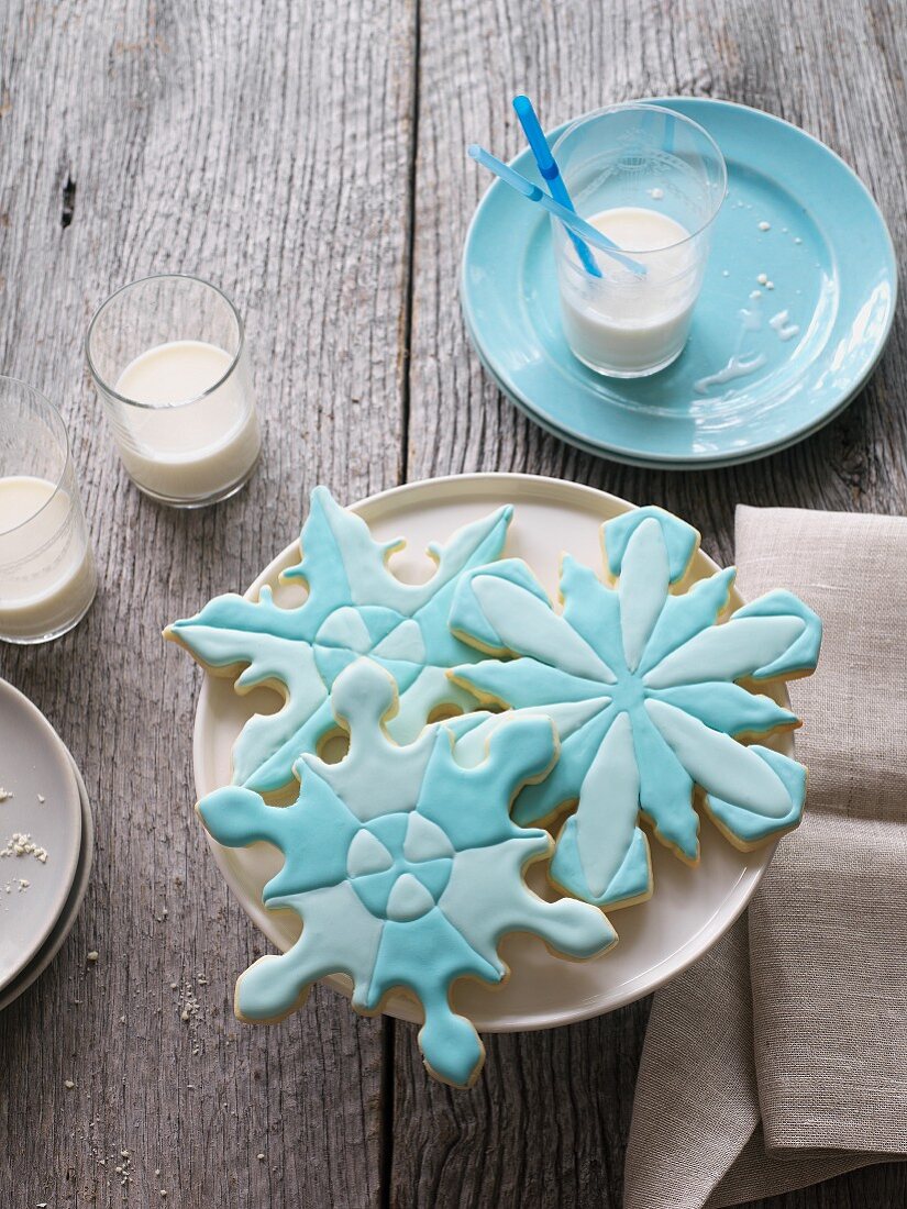 Snowflake cookies with blue icing and glasses of milk