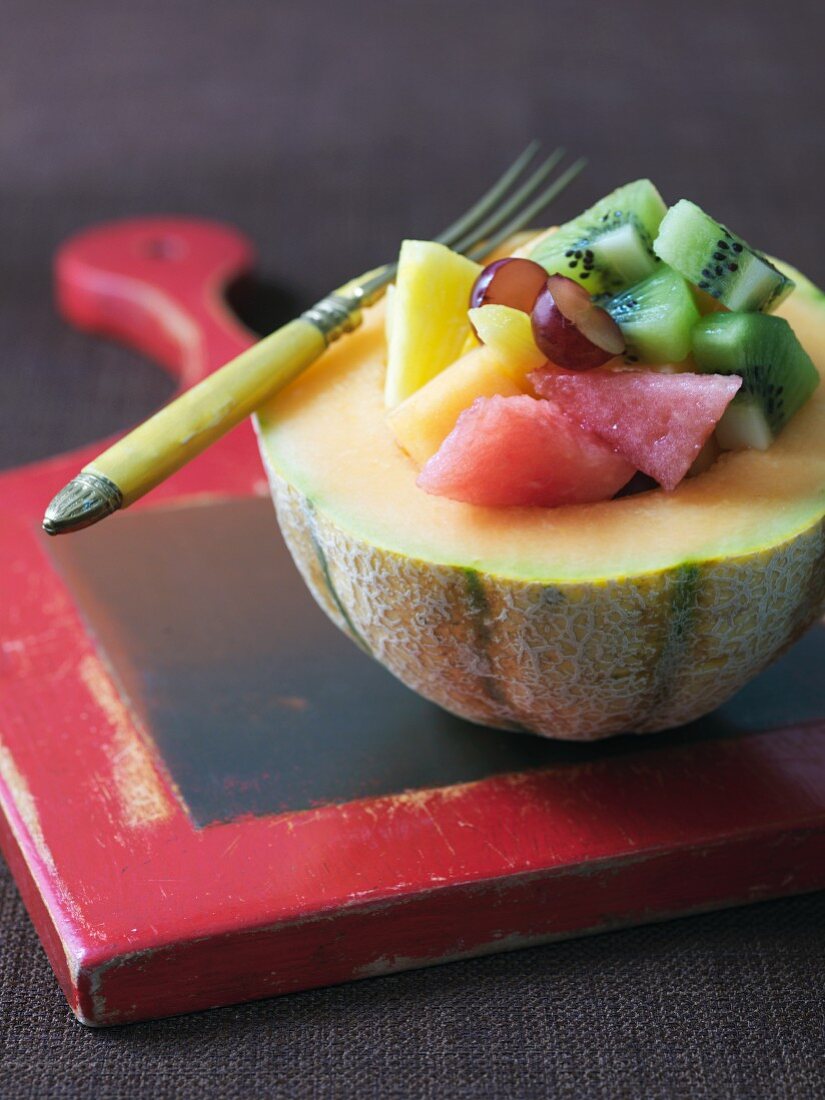 Fruit salad with kiwi, watermelon and grapes served in half a melon