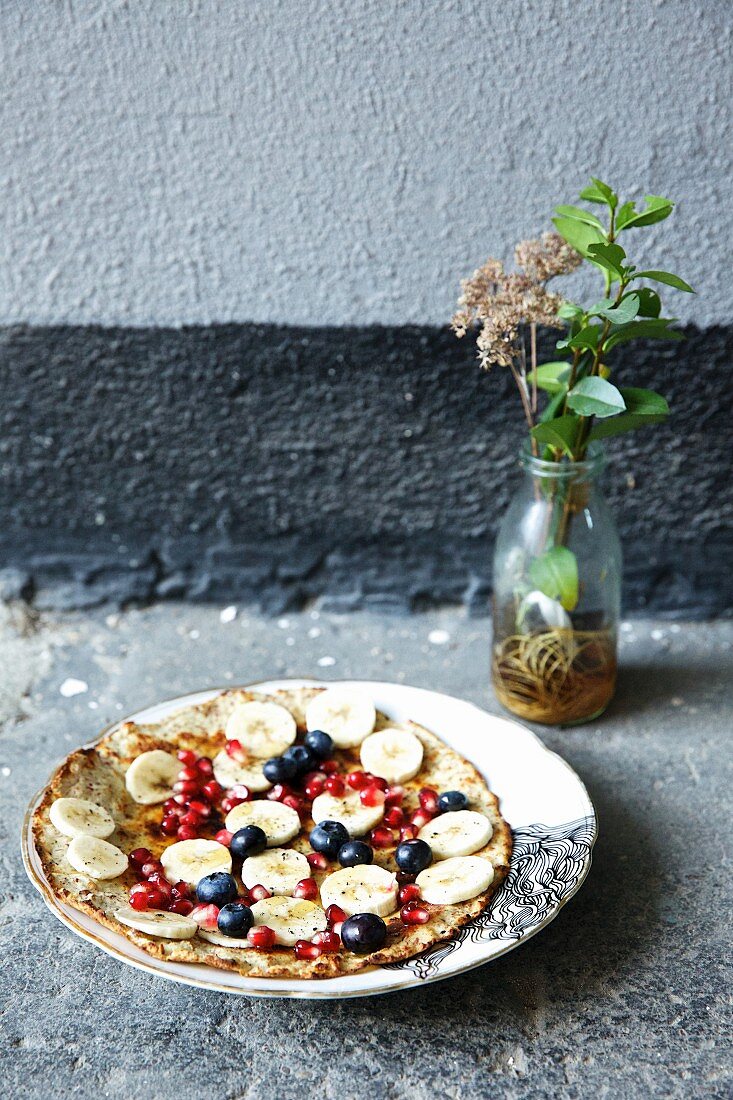 Almond pancake with bananas, pomegranate seeds and blueberries