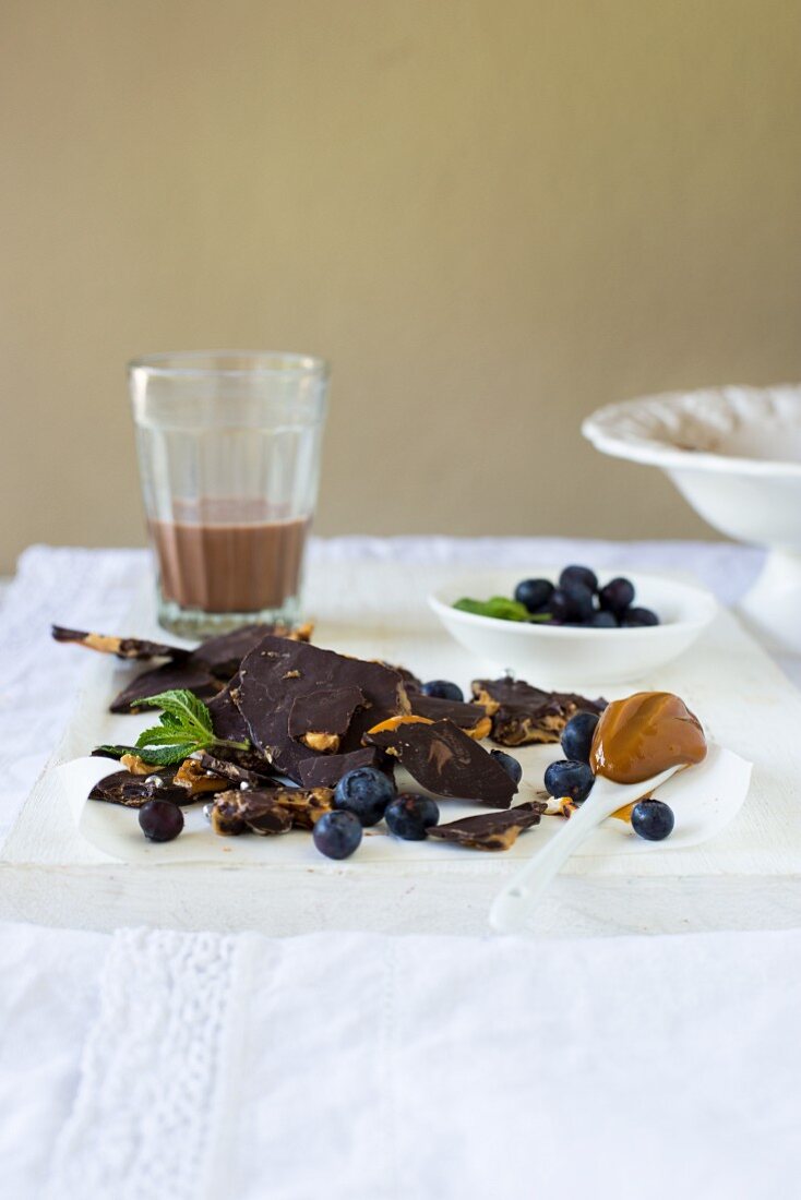 Dunkle Bruchschokolade mit Salted Caramel, frische Heidelbeeren und ein Glas Schokoladenmilch